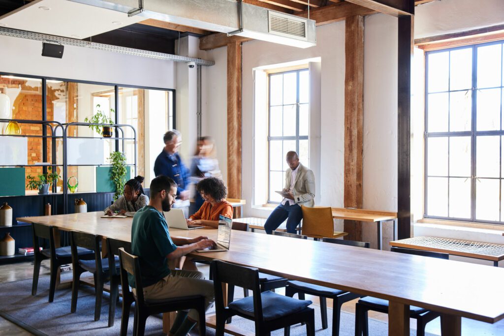 Diverse group of businessmen and businesswomen working together in an open plan area of a busy modern office