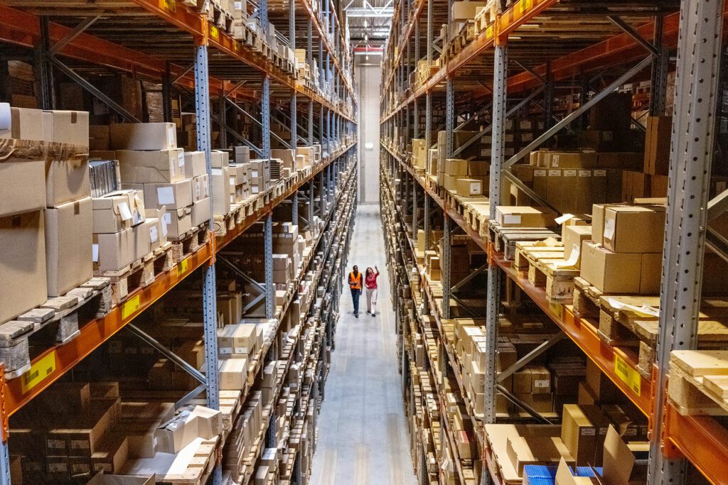 High angle view of a warehouse manager walking with foremen checking stock on racks