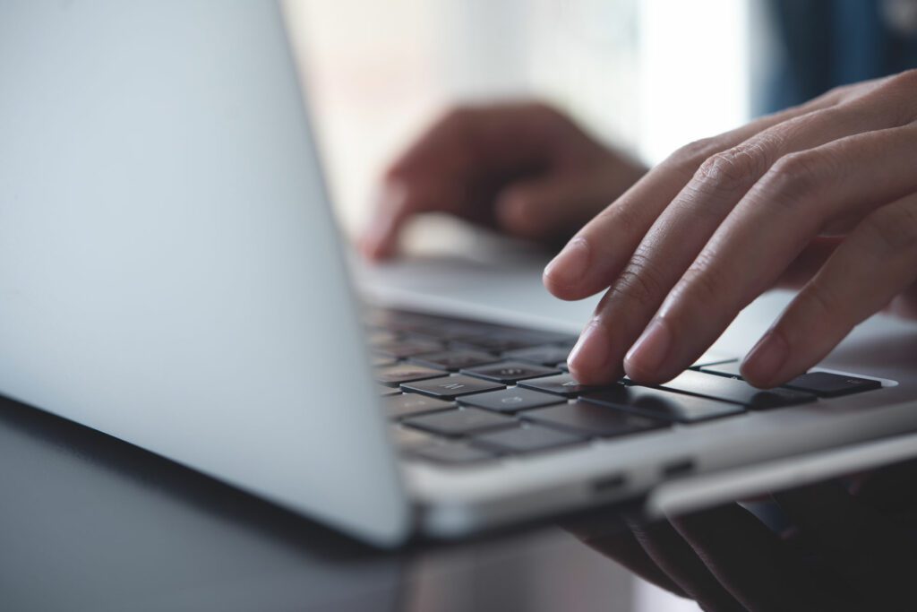 Close up of persons hands typing on laptop