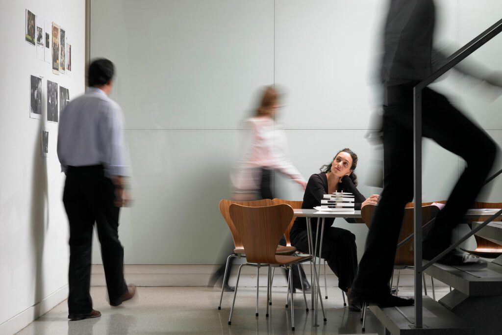 Colleagues walking in board room, woman sitting at conference table