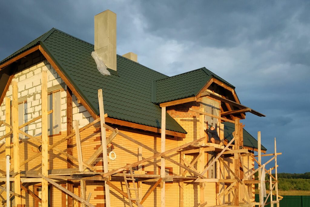 Insulation of the house with facade bricks, construction of a new house and scaffolding near the walls