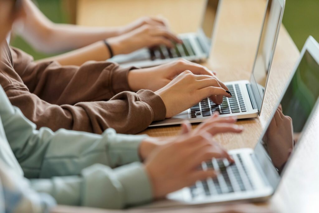 High school students sitting at the desk in the classroom during lesson, using laptops