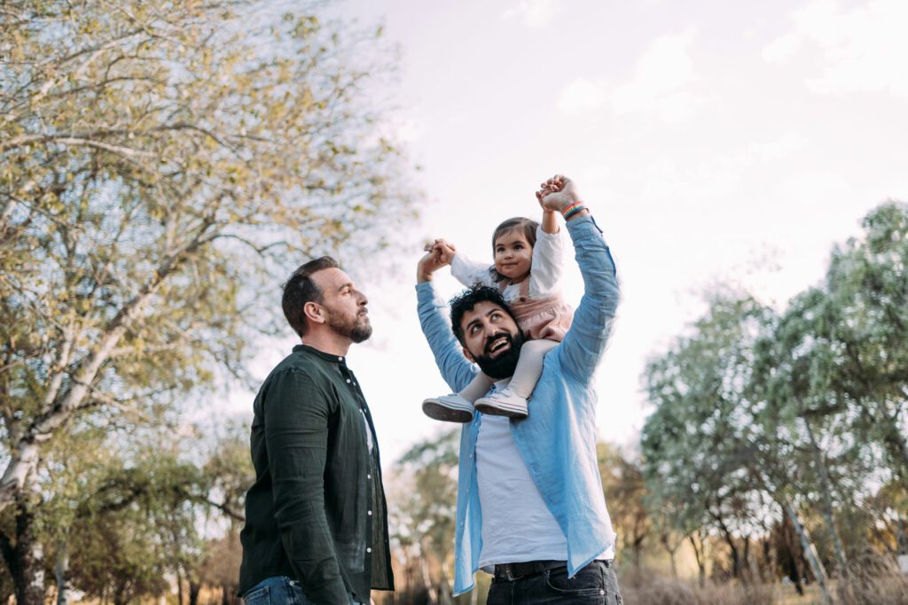 Gay couple with their young daughter enjoying a day in a park