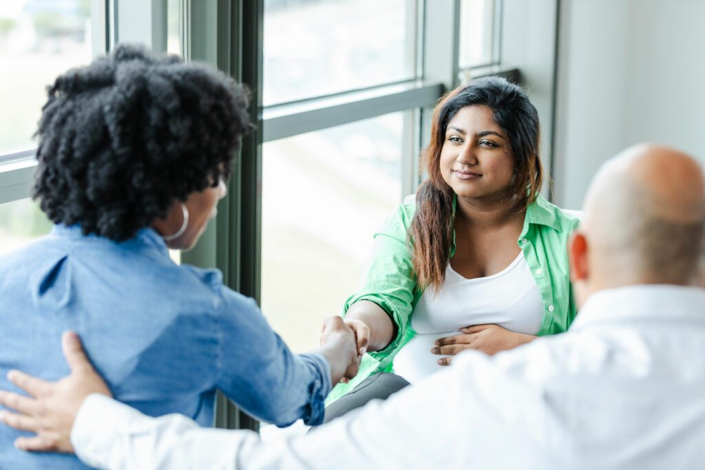 Unrecognizable intended mom shakes hands with surrogate