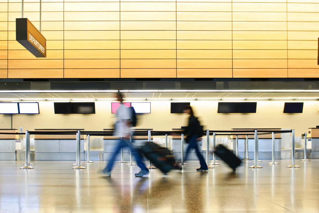 blurred motion of two people with suitcases walking towards the departure zone of an airport